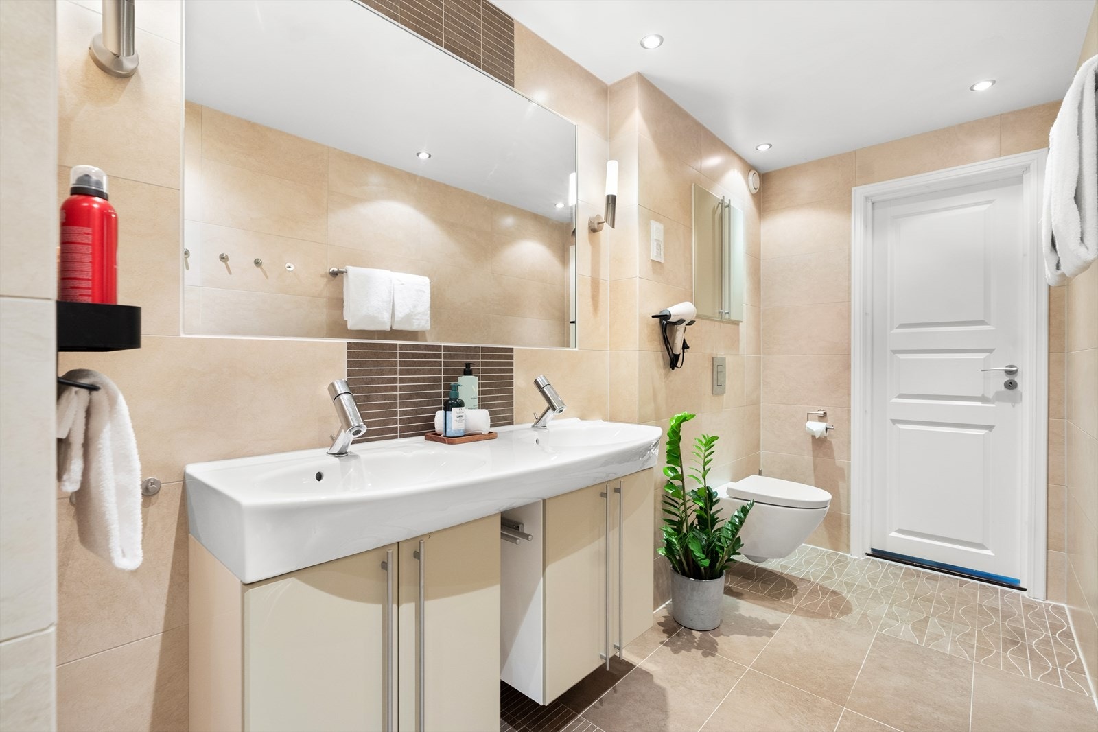 Delikat og romslig baderom med lys innredning med dobbelservant, vegghengt toalett og dusjnisje. Galleribilde