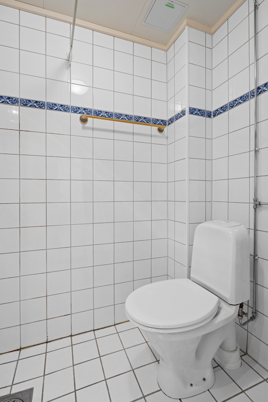 Badet inneholder frittstående toalett, dusj med dusjhjørner, servant med ett-greps blandebatteri, servantskap og opplegg for vaskemaskin. Galleribilde