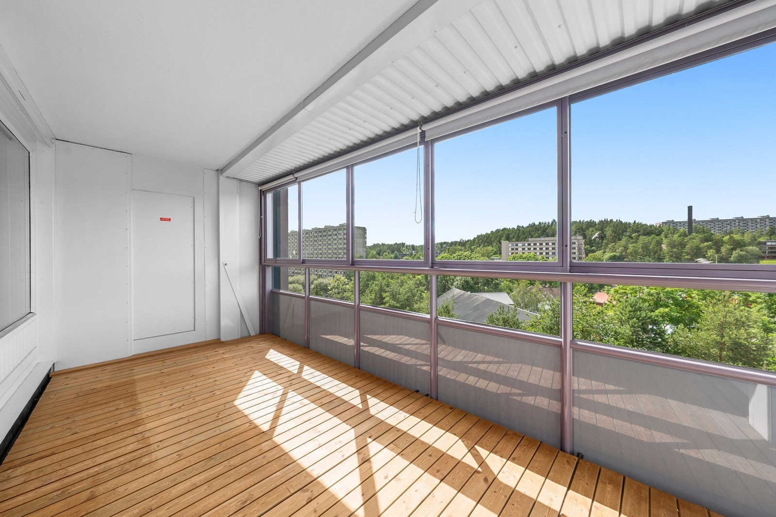 Stor innglasset balkong på 11 kvm med terrassebord og persienner. Galleribilde