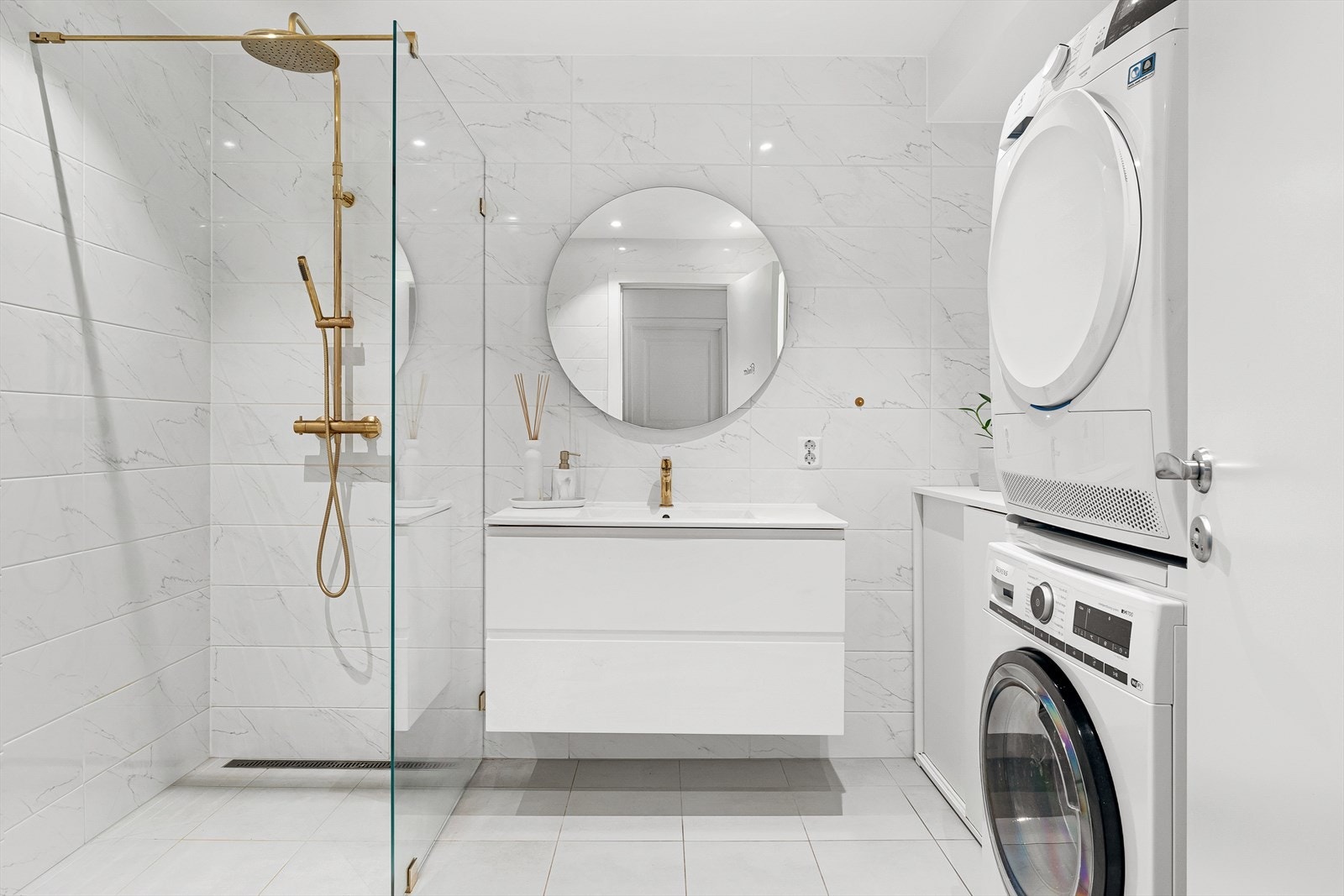 Badet er av god størrelse med praktisk løsning for vaskemaskin og tørketrommel, med tilhørende oppbevaring og brettebenk. Galleribilde