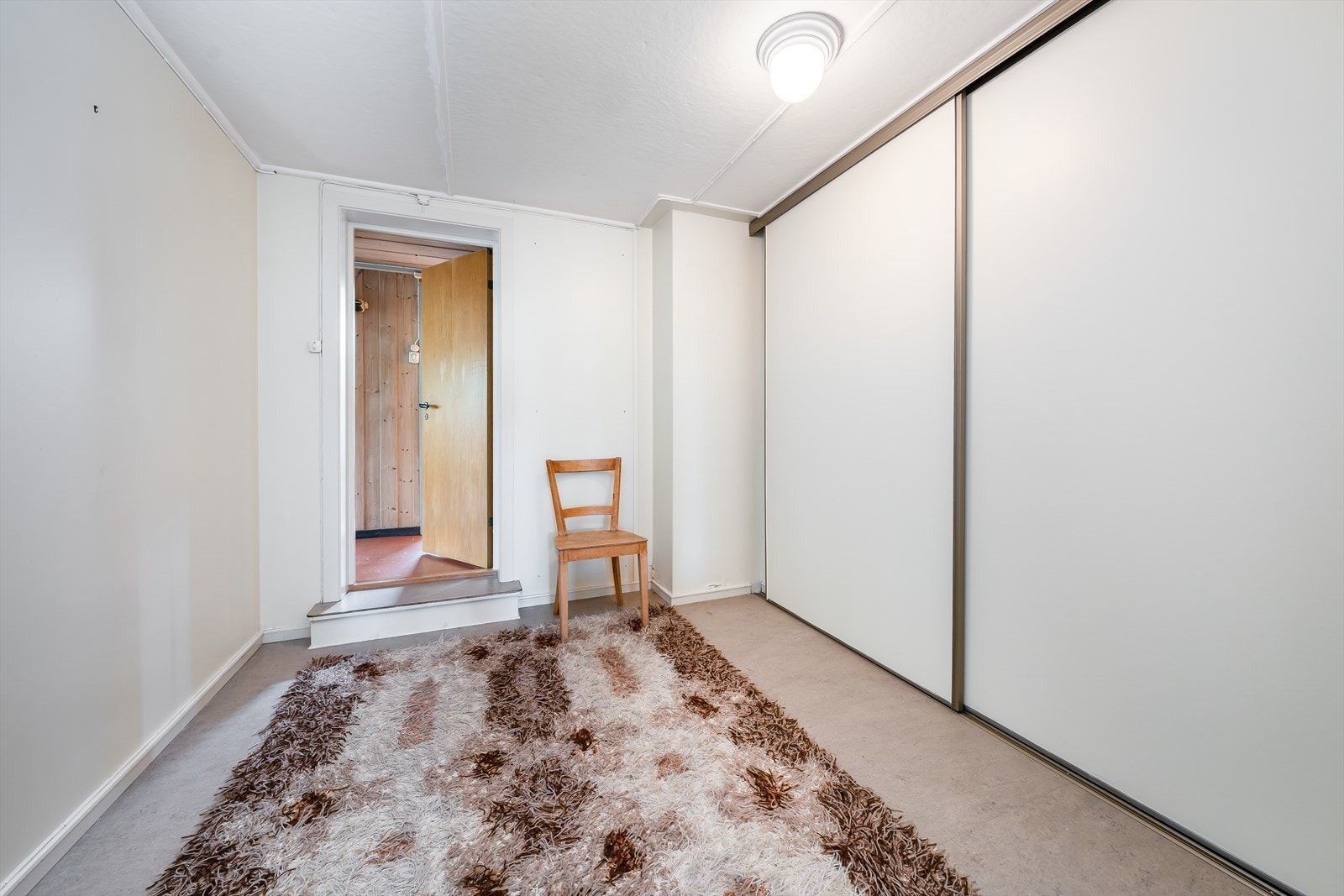 I kjeller er det et praktisk garderoberom med romslig skyvedørsgarderobe med slette hvite fronter på dørene. Galleribilde