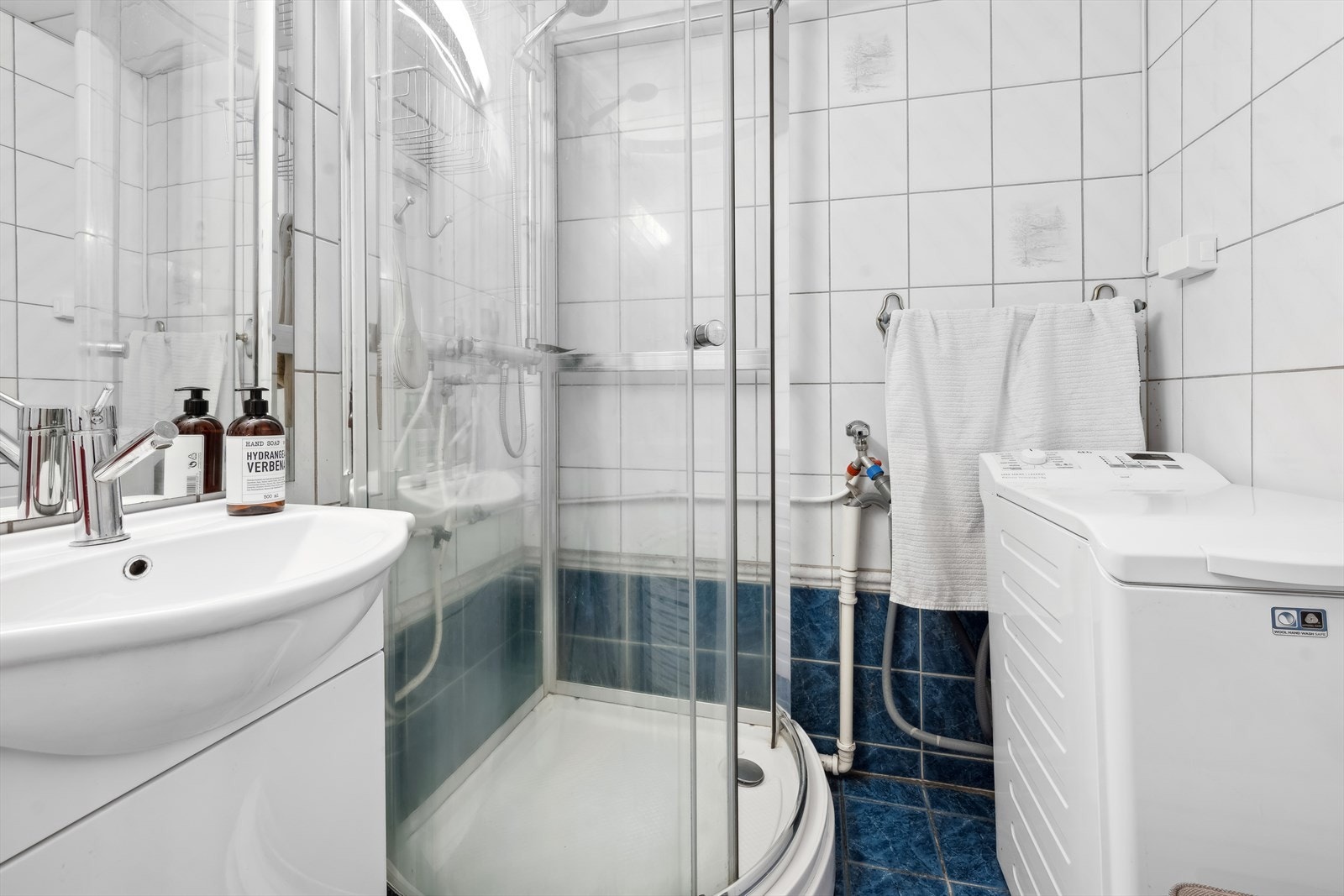 Badet har enkel servant med underskap, dusjkabinett og opplegg for vaskemaskin. Galleribilde