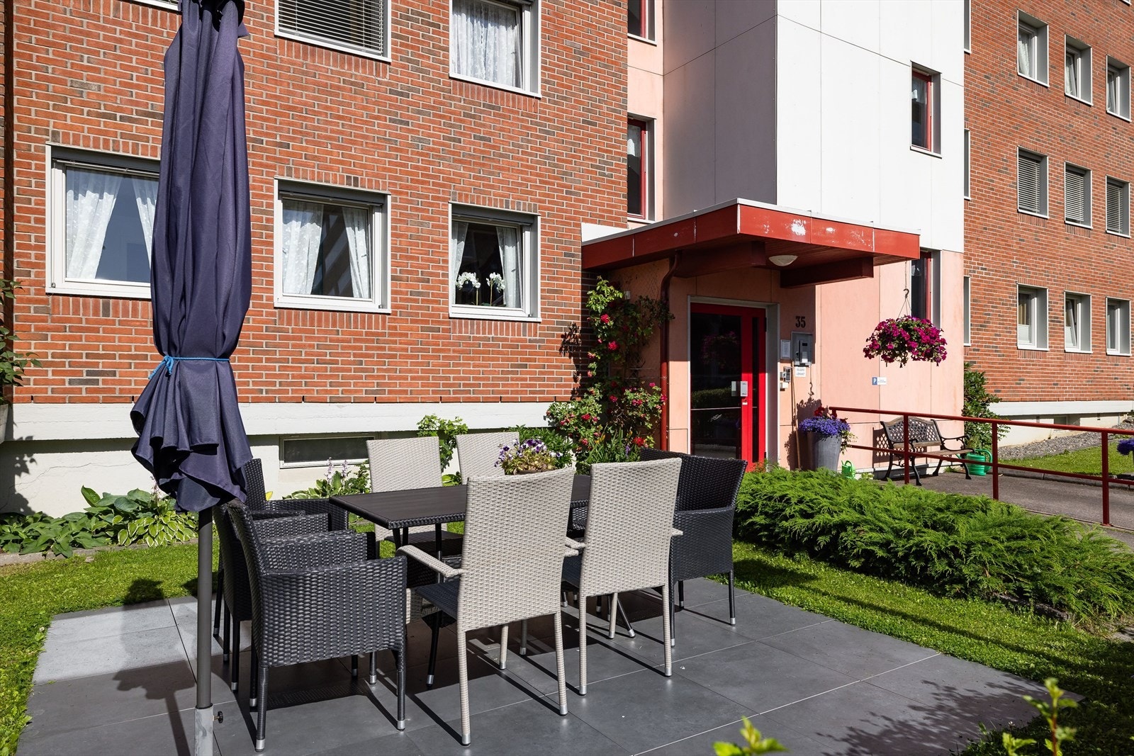 Hyggelig terrasse med sittegruppe og parasoll utenfor inngangspartiet. Galleribilde