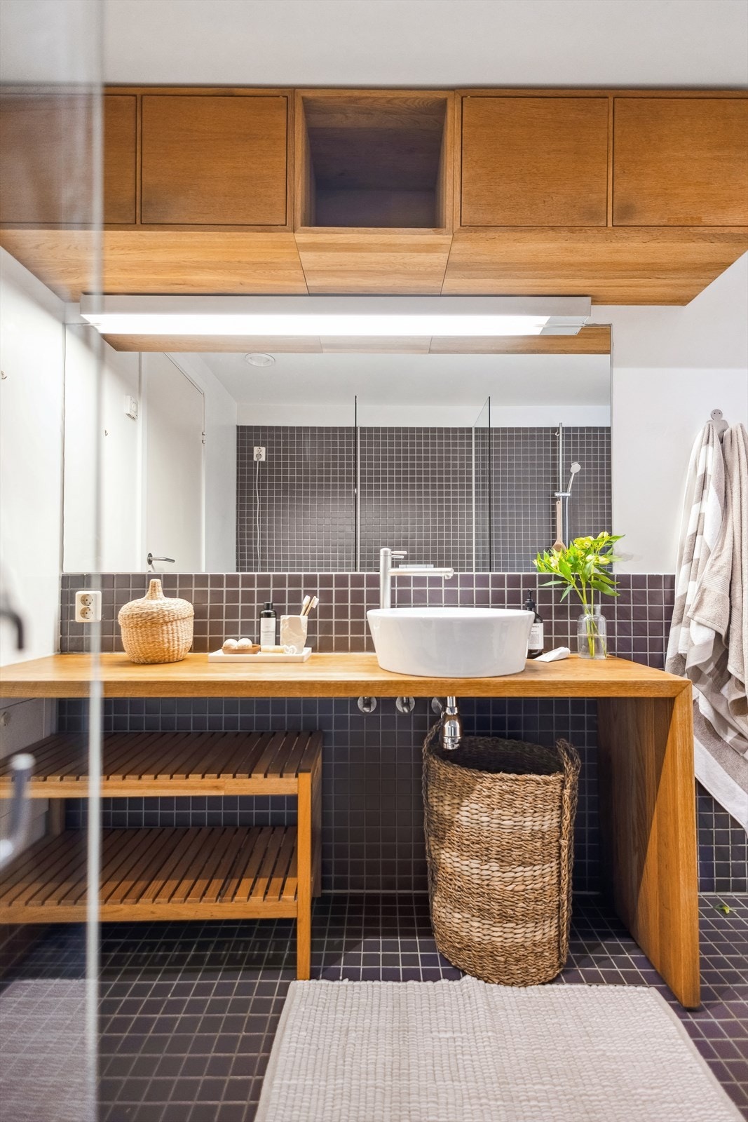 Badet er innredet med et dusjhjørne, veggmontert toalett, en innredning i eik med skålservant og speil. Galleribilde