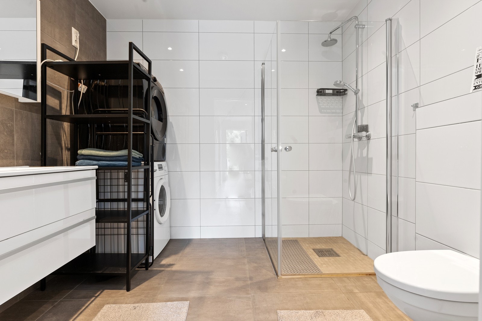 Badet i underetasjen har nedfelt servantinnredning, veggmontert toalett og dusjhjørne med glassdører. Her er det også opplegg for vaskemaskin samt varme i gulv Galleribilde