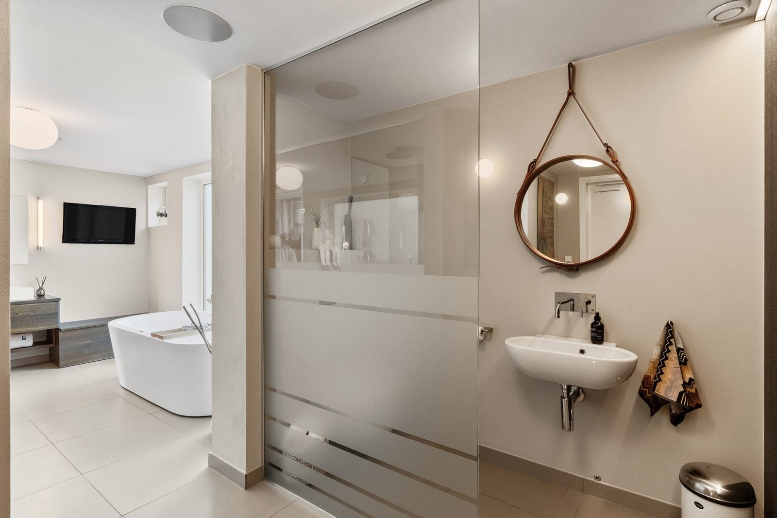 Moderne bad med stilrene detaljer, frittstående badekar og dusjvegg i glass. Lys og romslig atmosfære som skaper velvære. Galleribilde