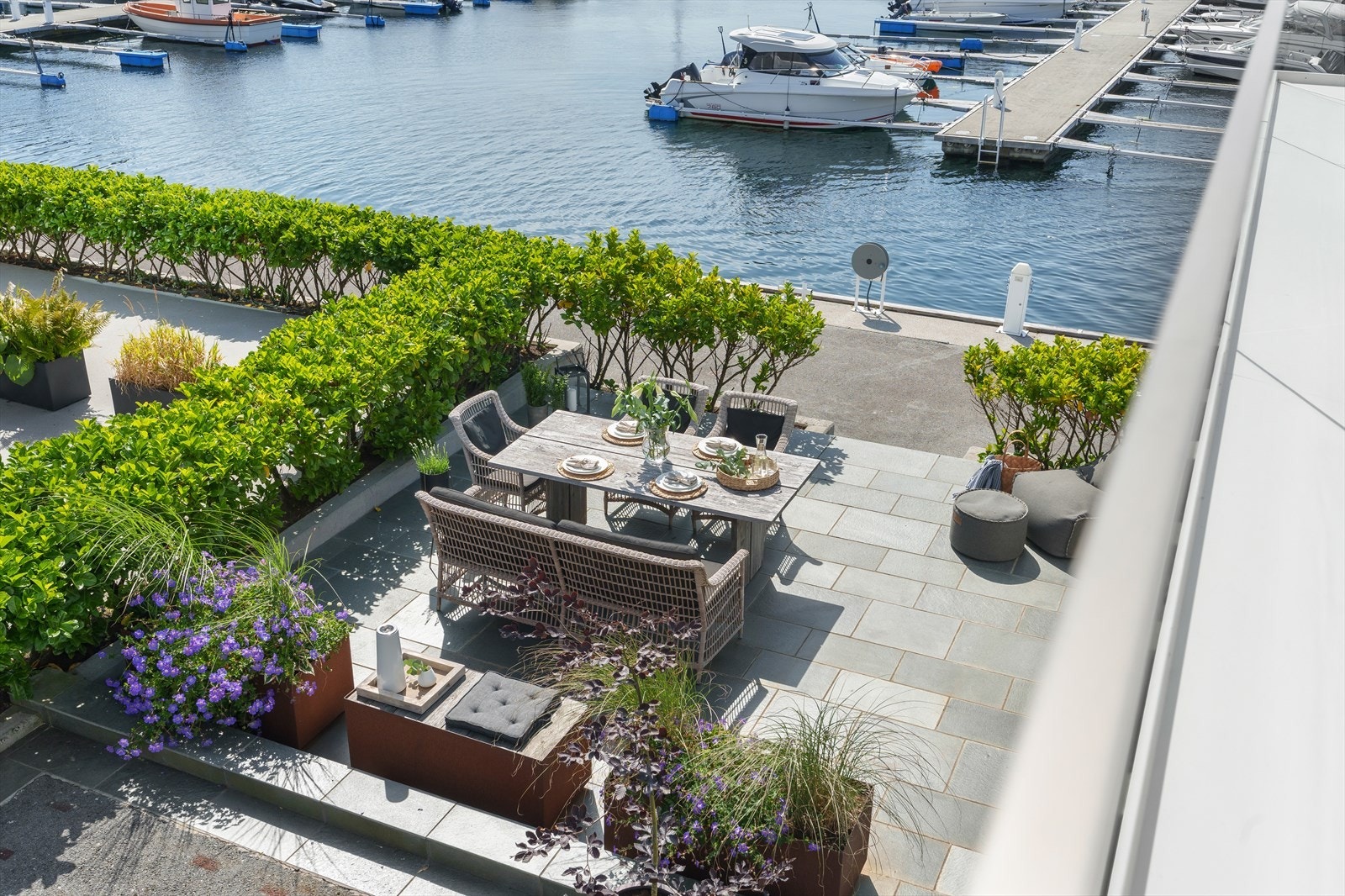 Moderne uteplass ved marina, med frodig beplantning og utsikt over båthavn. Perfekt for avslapning og sosiale sammenkomster. Galleribilde