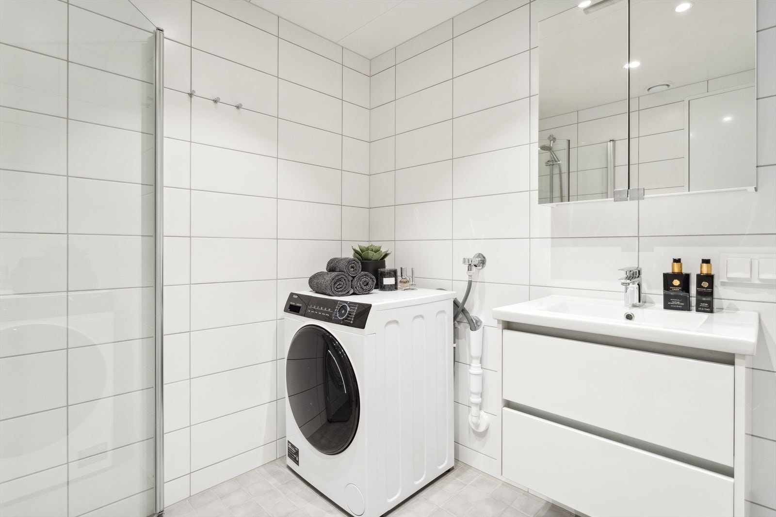 Badet er utstyrt med servant med skuffer, dusjhjørne, vegghengt toalett og opplegg for vaskemaskin. Galleribilde