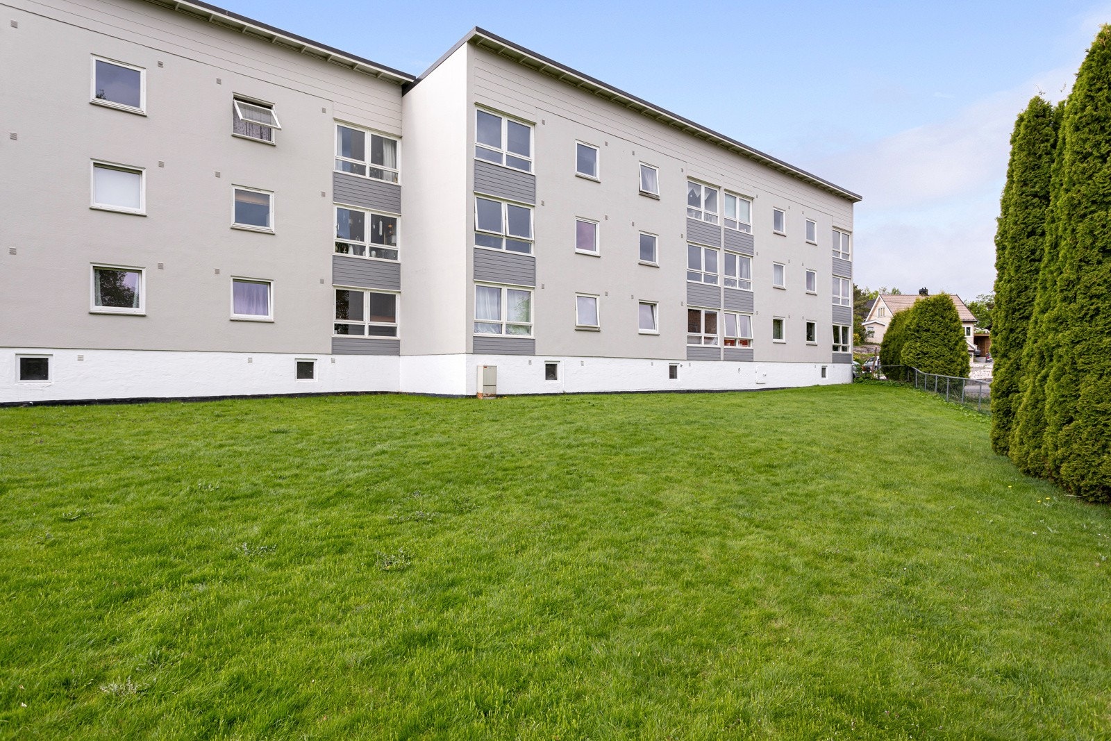 Stort, grønt fellesareal med lekeplass og parkering. Galleribilde