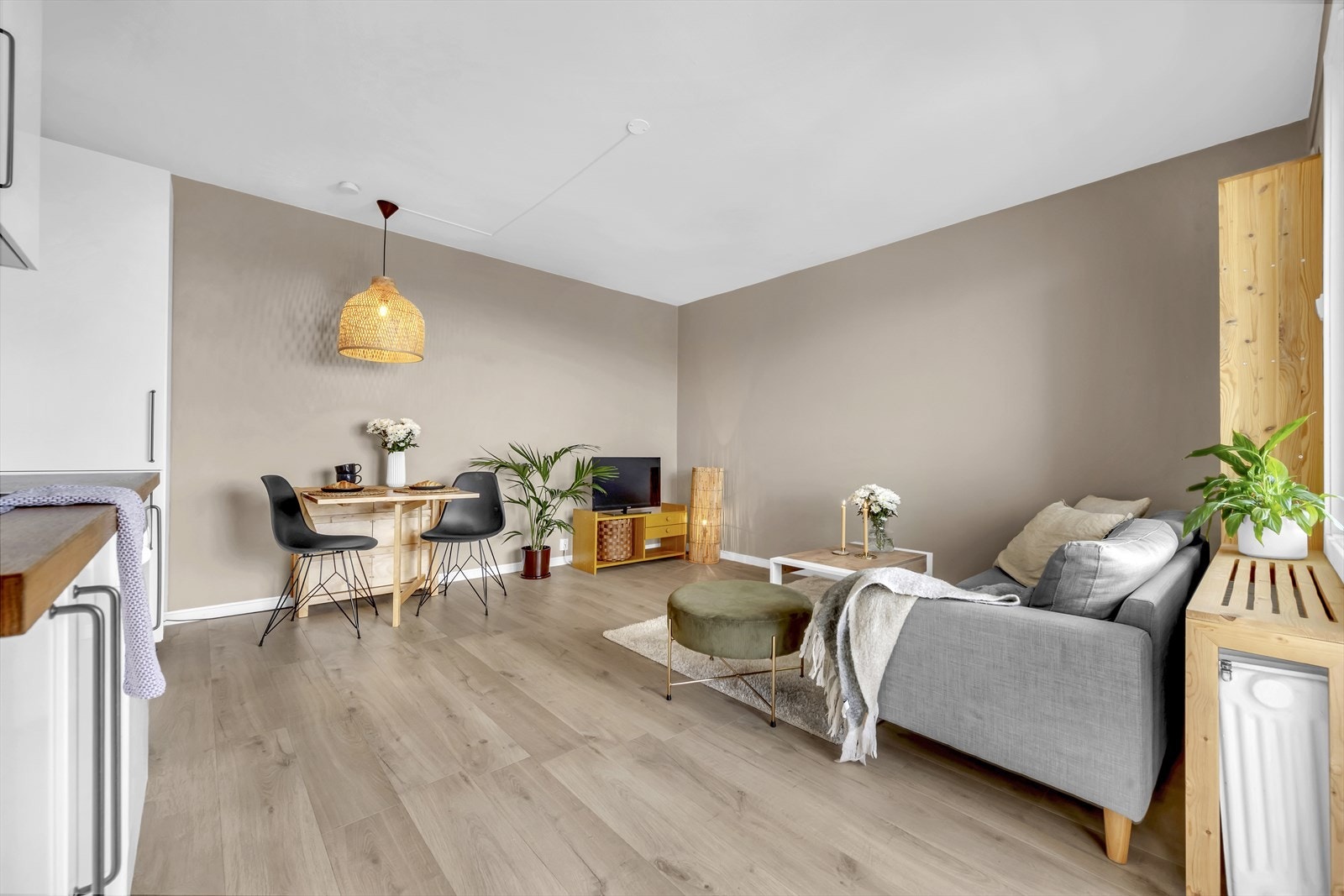 Stue og kjøkken i en åpen sosial løsning med plass til både sofa, tv-seksjon og spisegruppe. Galleribilde