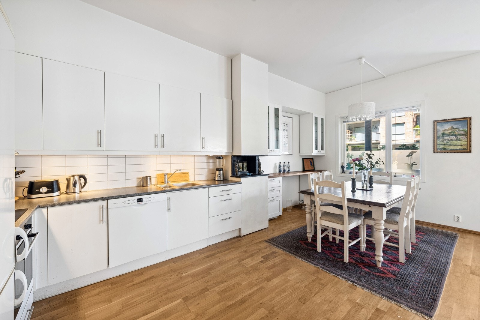 Fin kjøkkeninnredning med lyse hvite fronter av variert utforming. God skap og benkeplass. Galleribilde