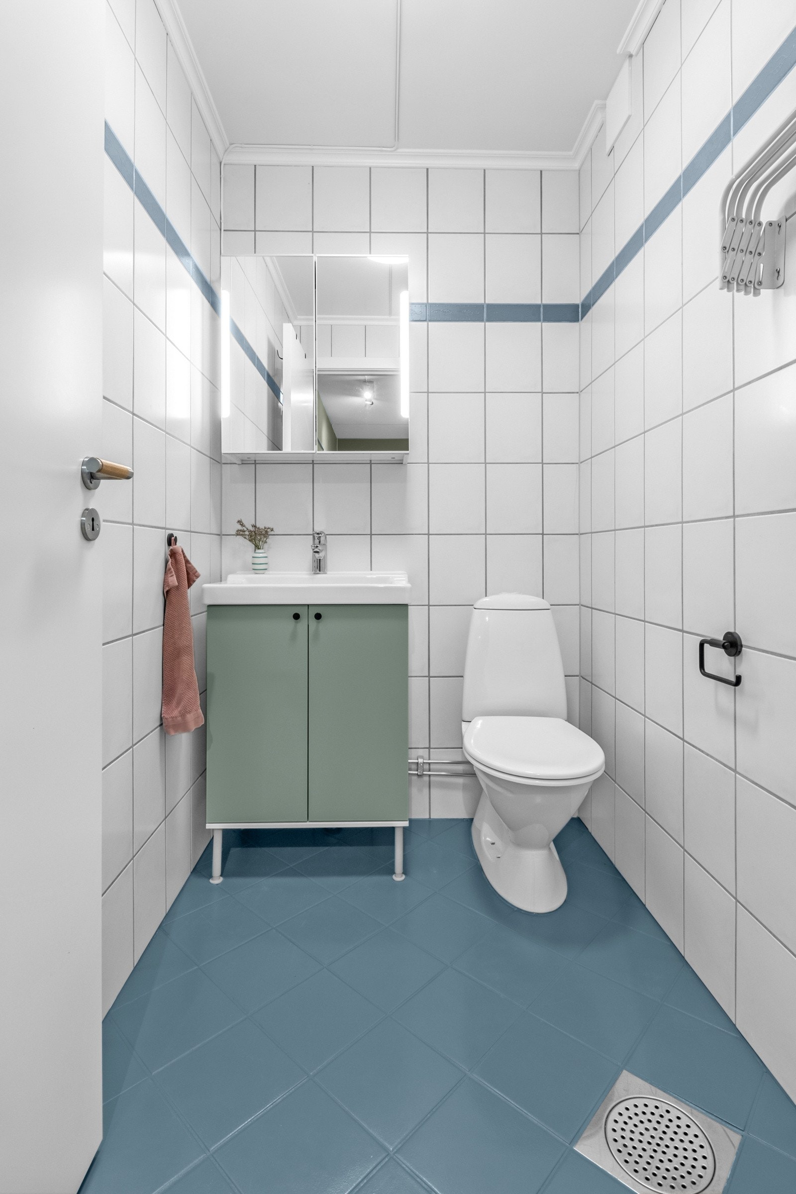 Flislagt toalettrom/wc utstyrt med gulvstående toalett, servant med innredning og speilskap med belysning. Det er varmekabler i gulv. Galleribilde