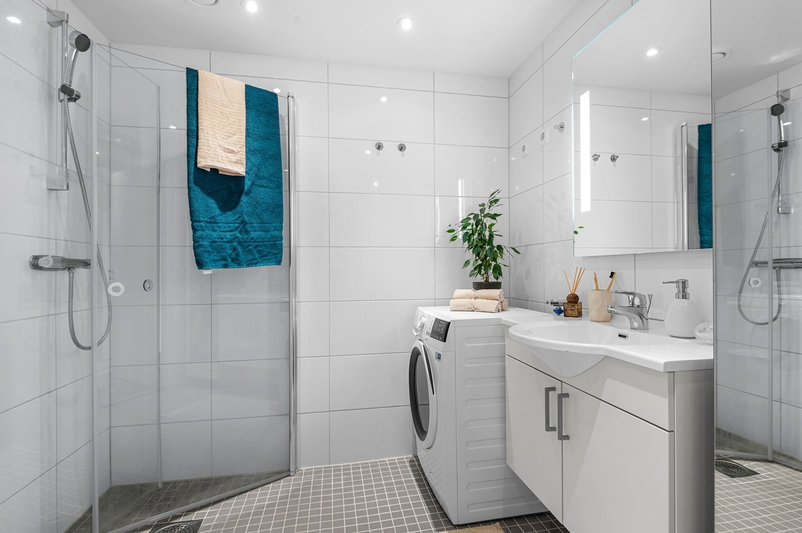 Baderommet på 4,5 m² har lyse, delikate fliser fra topp til tå og varme i gulv som sikrer en god start på dagen. Baderomsinnredningen er levert av HTH og har gunstige oppbevaringsløsninger til blant annet håndduker og baderomsartikler. Galleribilde