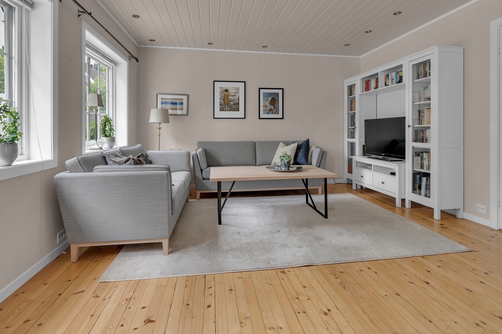 Romslig og lys stue med slipte tregulv og spotter langs taket Galleribilde