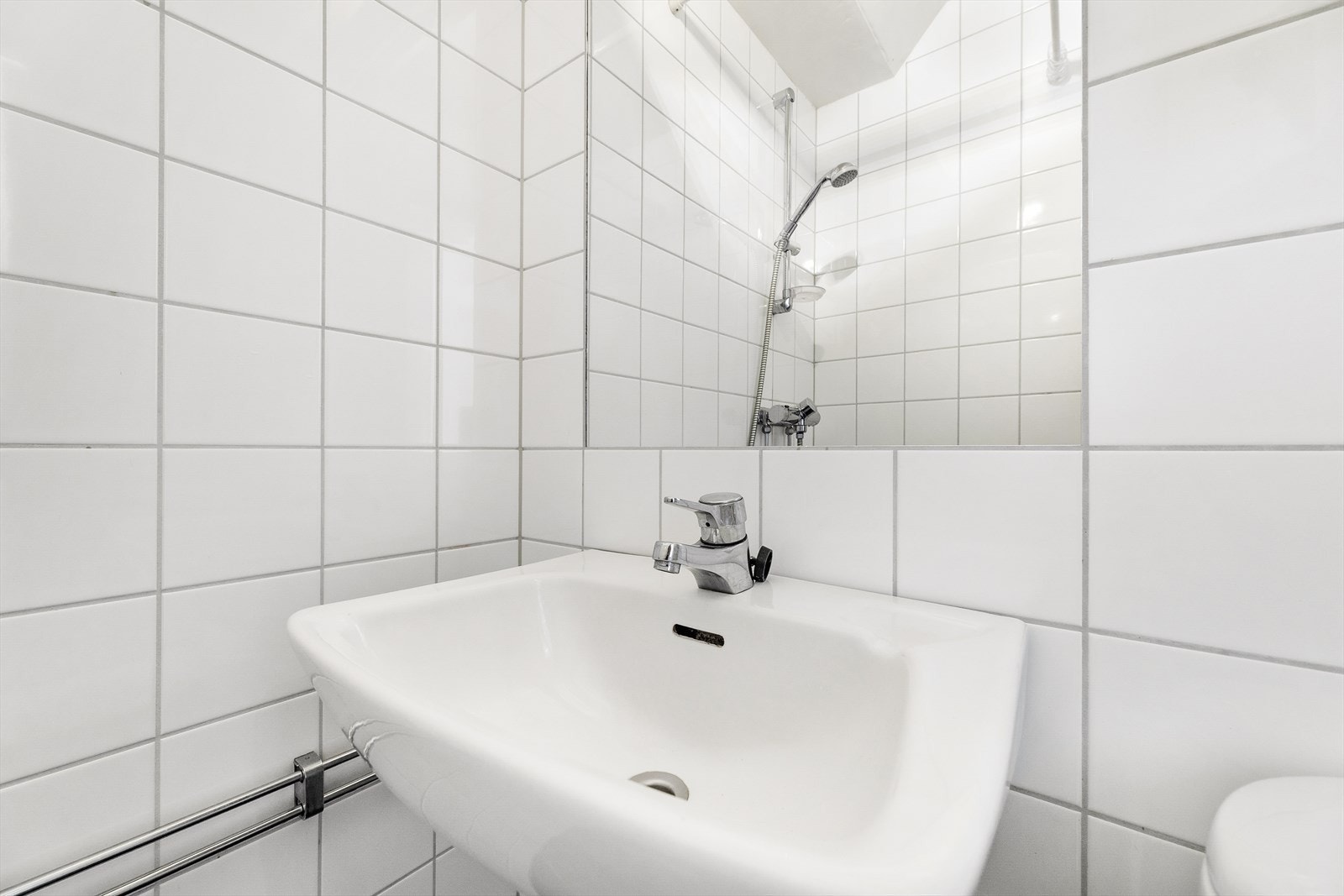 Badet er utstyrt med dusjhjørne med forheng, gulvstående wc og enkel servant Galleribilde