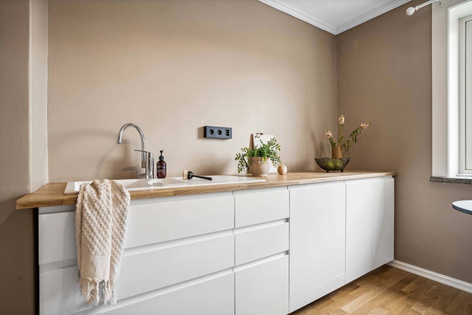 Kjøkkeninnredning fra IKEA med hvite slette fabrikklakkerte fronter, heltre benkeplate, oppvaskkum, ventilator med kullfilter og opplegg for oppvaskmaskin. Galleribilde