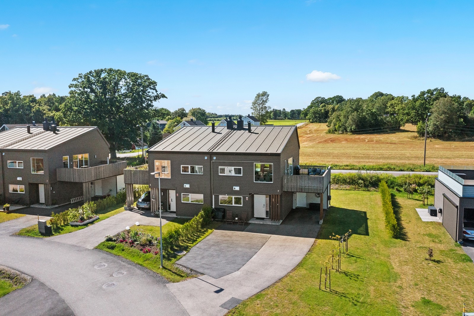 Innkjørselen er asfaltert og her er det rikelig med parkeringsplass - det er også en carport med el-billader Galleribilde