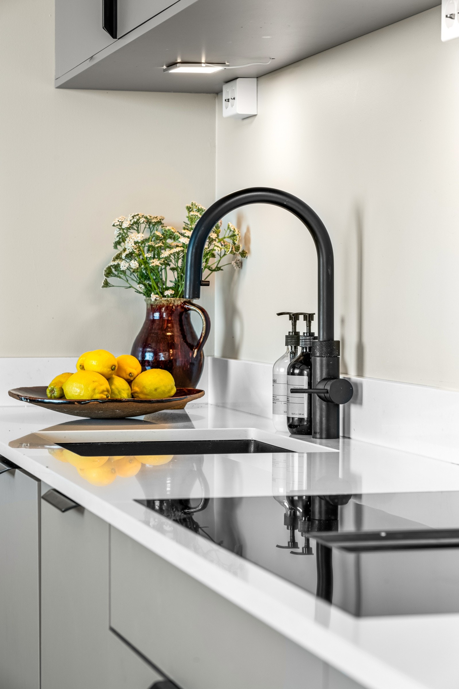 Kjøkkenkranen er holdt i moderne, sort utførelse og har Quooker-funksjon som gir kokende vann. Platetopp med integrert kullfilterventilator. Galleribilde
