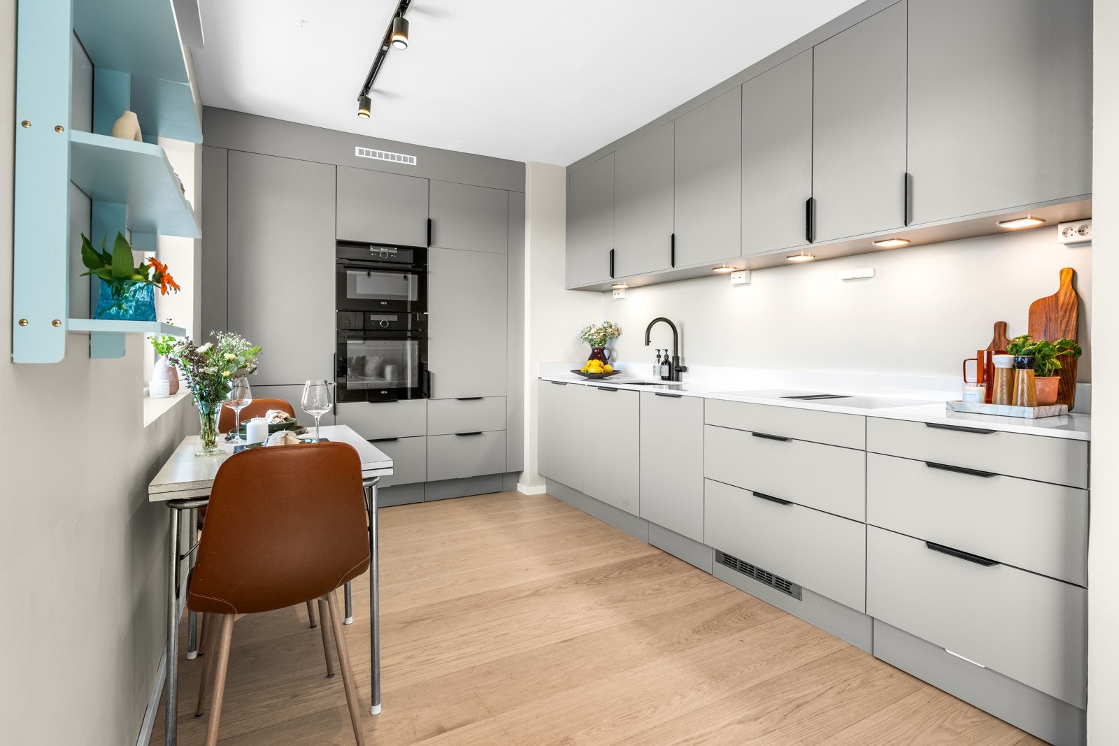 Kjøkkeninnredningen har takhøye skap med grå, glatte fronter, sorte håndtak, dempefunksjon, benkeplater av kompositt stein, og underlimt vaskekum i silgranitt. Galleribilde