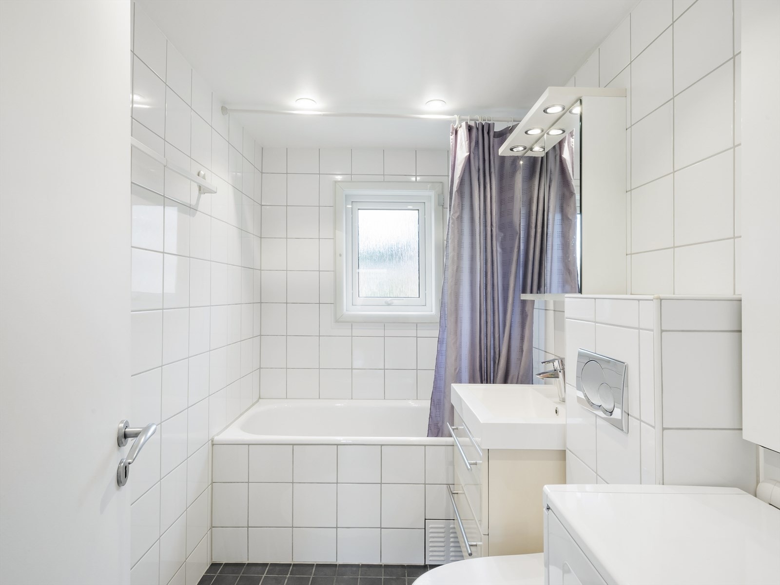 Moderne, flislagt bad med varmekabler i gulv og downlights i tak. Galleribilde