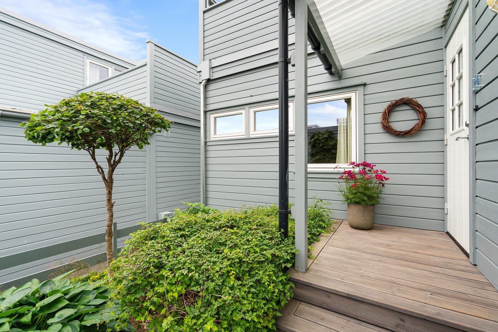 Boligen har en privat og velholdt inngang med dekorative planter. Galleribilde