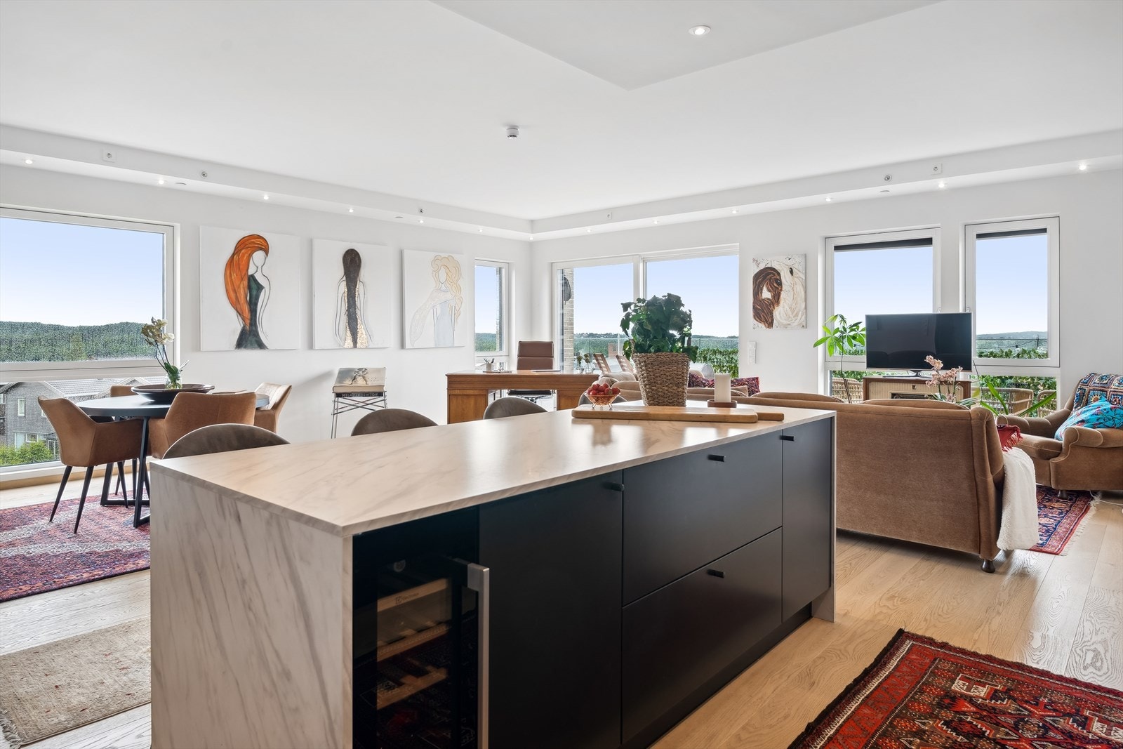 Med åpen løsning mot stuen gir dette et luftig uttrykk, samtidig som kjøkkenøyen gir et naturlig skille av rommet Galleribilde