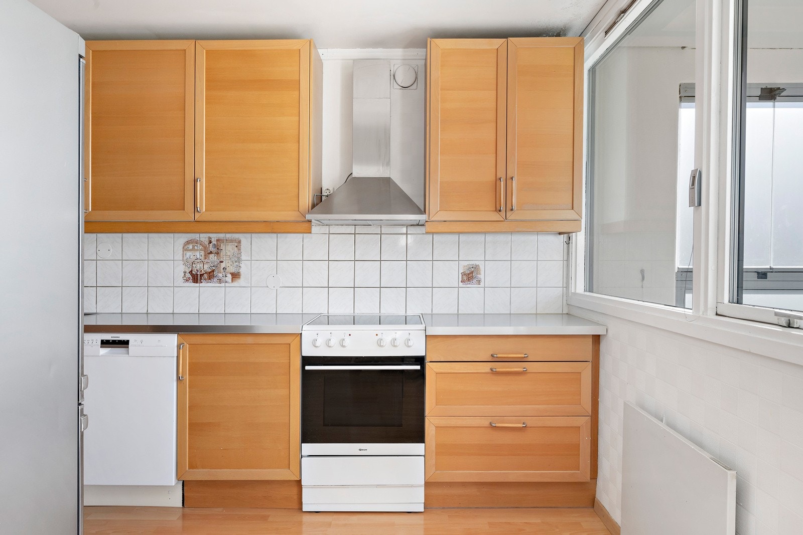 Kjøkkeninnredning med profilerte fronter og laminat benkeplate. Det er fritthengende kjøkken ventilator i stål med kullfilter. Det er ikke montert automatisk vannstopper eller komfyrvakt. Galleribilde
