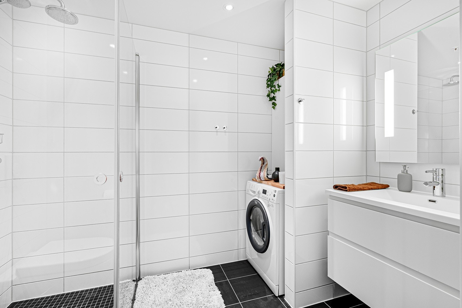 Lekkert, flislagt bad med praktisk løsning for vaskemaskin og tørketrommel. Galleribilde