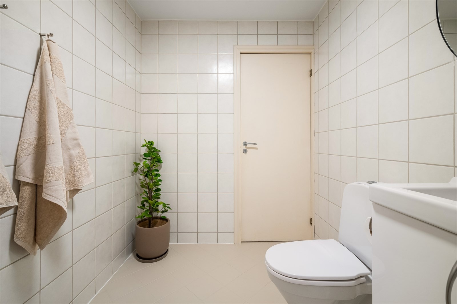 - Badet er innredet med gulvmontert toalett, benkeskap med servant, opplegg for vaskemaskin og dusjdører i glass - Galleribilde