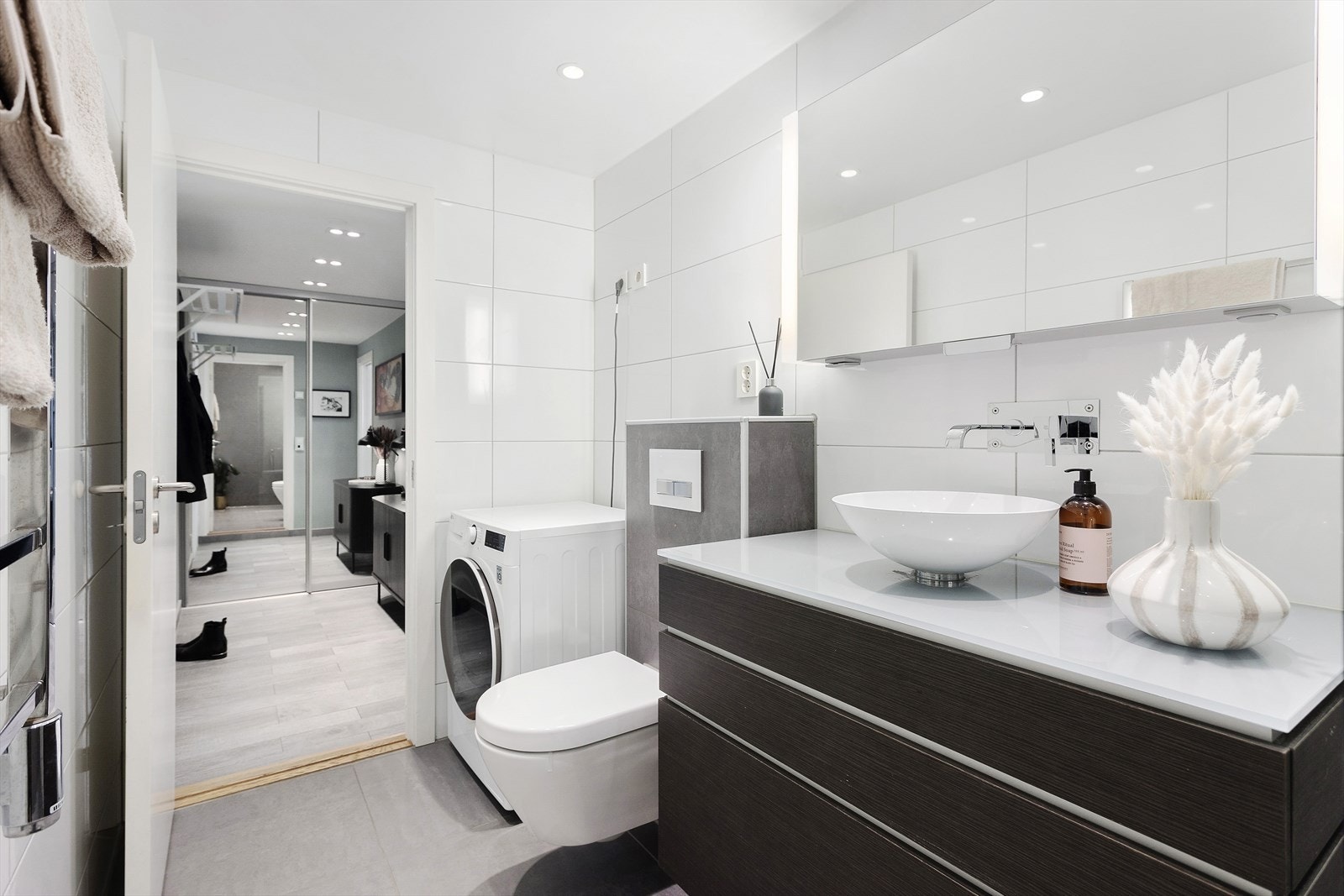 Videre er badet utstyrt med veggmontert wc, dusjnisje med glassdør i herdet glass, ettgreps dusjbatteri i rustfritt stål fra Tapwell med 2 dusjhoder (håndholdt og regnfall). Opplegg for vaskemaskin Galleribilde