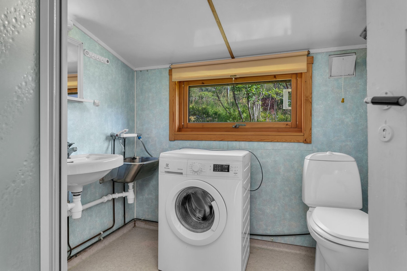 Bad / vaskerom fra ca. 1991. Rommet er utstyrt med servant, toalett, dusjkabinett, samt skyllekar med vanntilførsel for vaskemaskin. Galleribilde