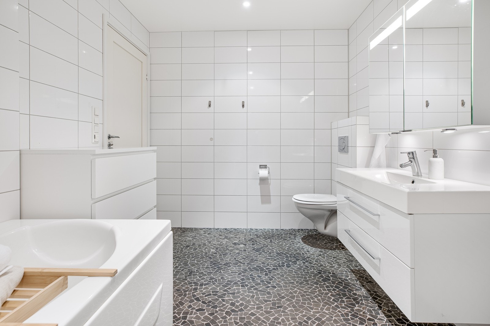 Badet er innredet med vegghengt toalett, dusjkabinett, et delikat badekar og en flott baderomsinnredning med nedfelt servant Galleribilde