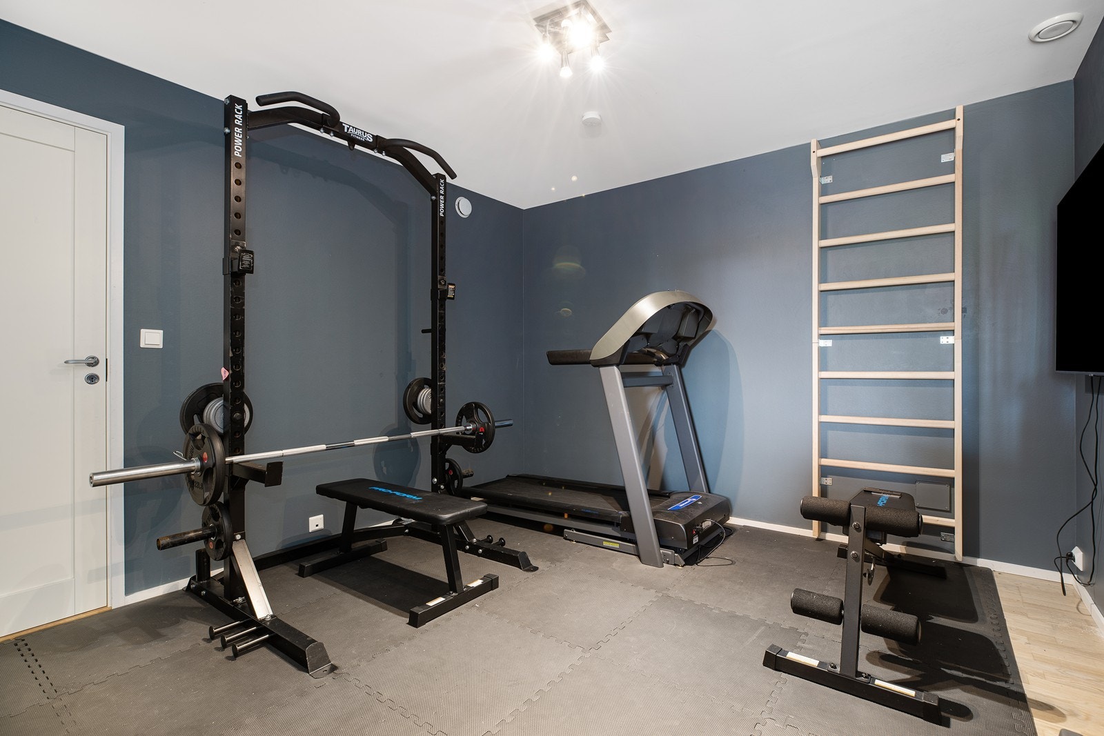 Tv-stue/treningsrom med parkettgulv og stilige farger på veggene. Rommet gir ekstra plass til lek og aktivitet Galleribilde