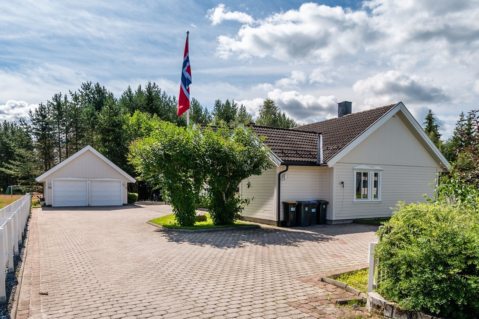 Tomten er pent opparbeidet med belegningsstein og beplantning, samt stor hage med plen og solrike terrasser mot vest. Galleribilde