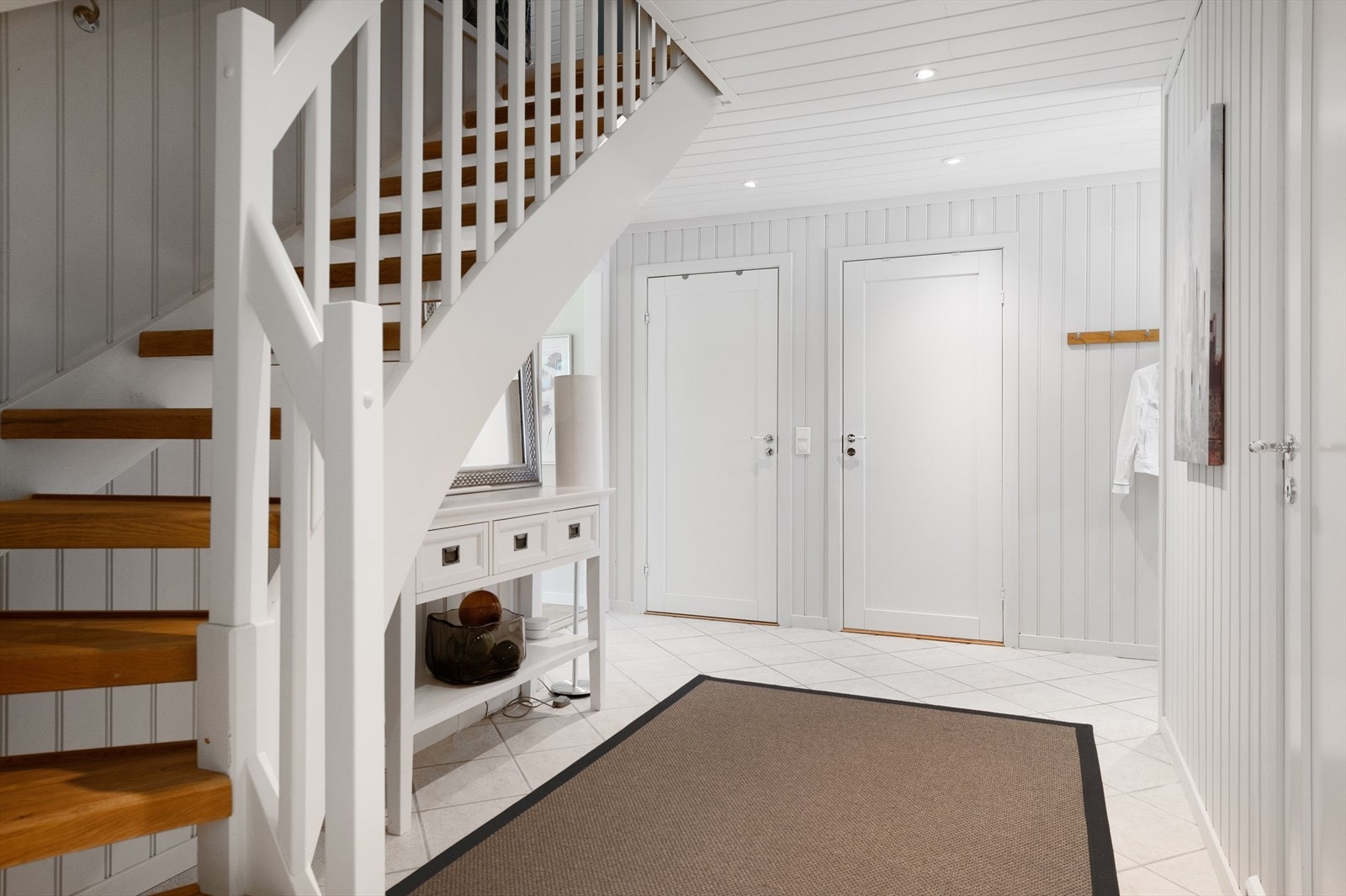 Entréen har god standard med lyse fliser på gulv med vannbåren gulvvarme, lysmalt panel på veggene og downlights i himlingen. Galleribilde