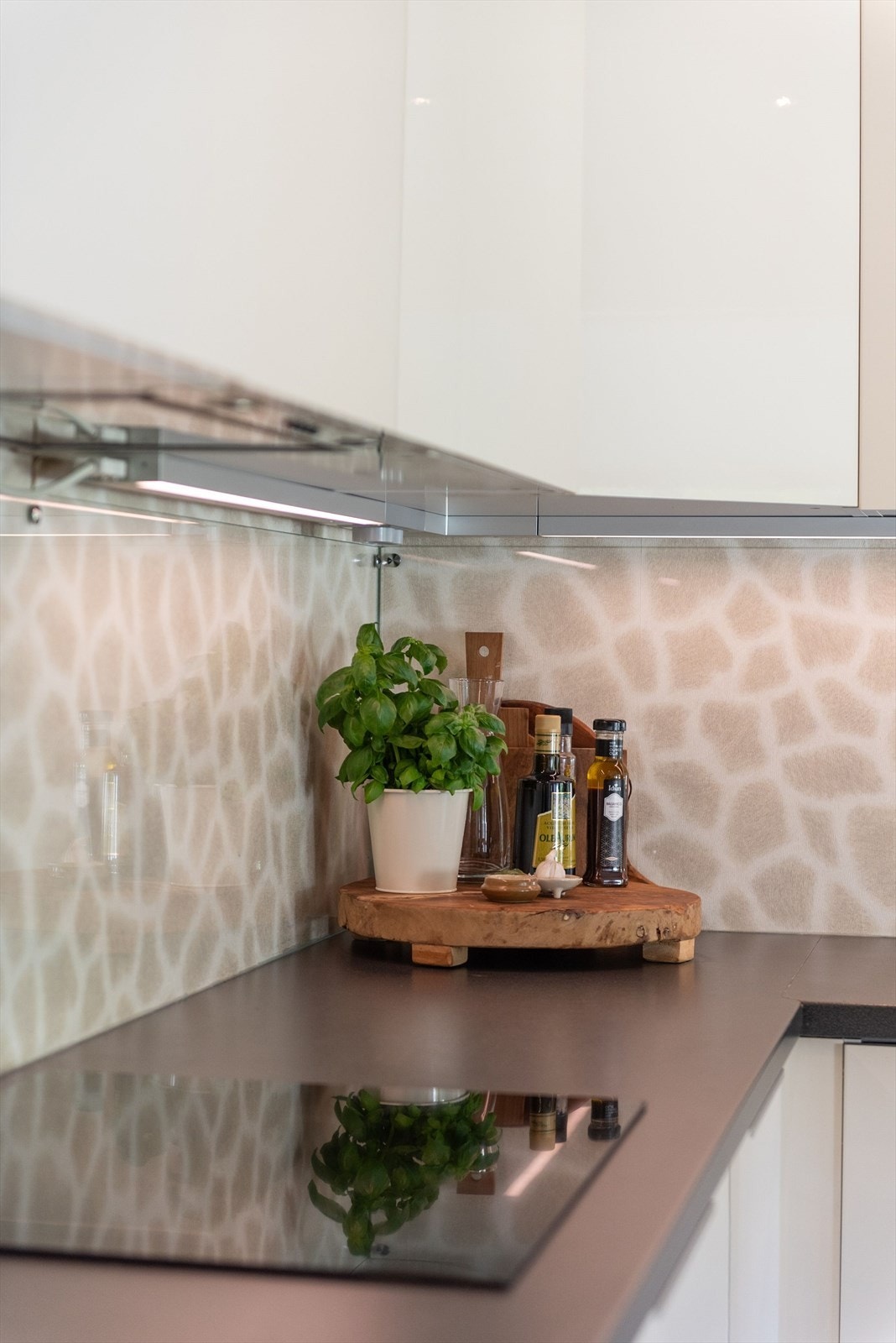 Innredningen har hvite glatte fronter og laminert benkeplate med nedfelt oppvaskkum. Praktisk med glassplater i benkeryggen og belysning under overskapene. Galleribilde