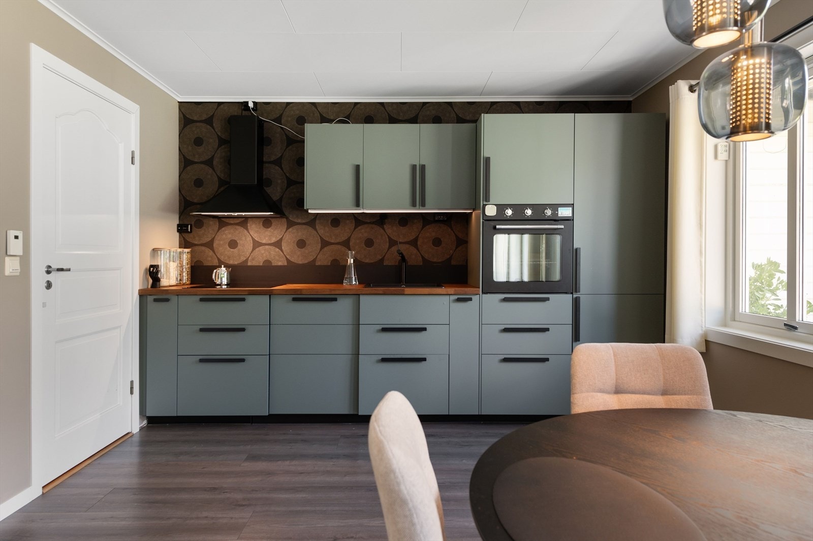 Nyere kjøkkeninnredning med glatte fronter og heltre benkeplate med nedfelt oppvaskkum. Kjøkkenet er fullt utstyrt med integrerte hvitevarer som medfølger i handelen. Galleribilde