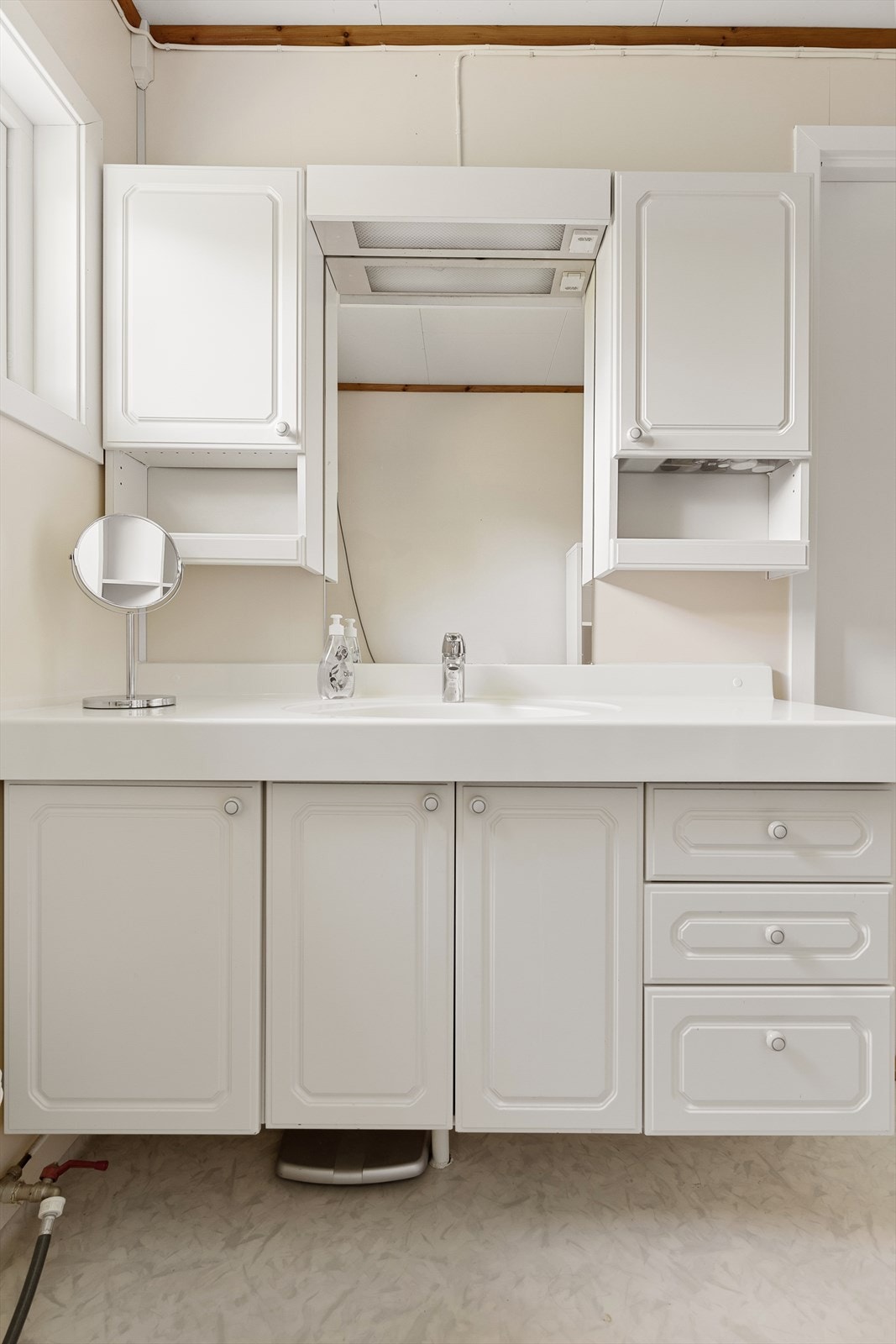 Baderomsinnredningen byr på rikelig med oppbevaringsplass bak hvite, profilerte fronter. Galleribilde