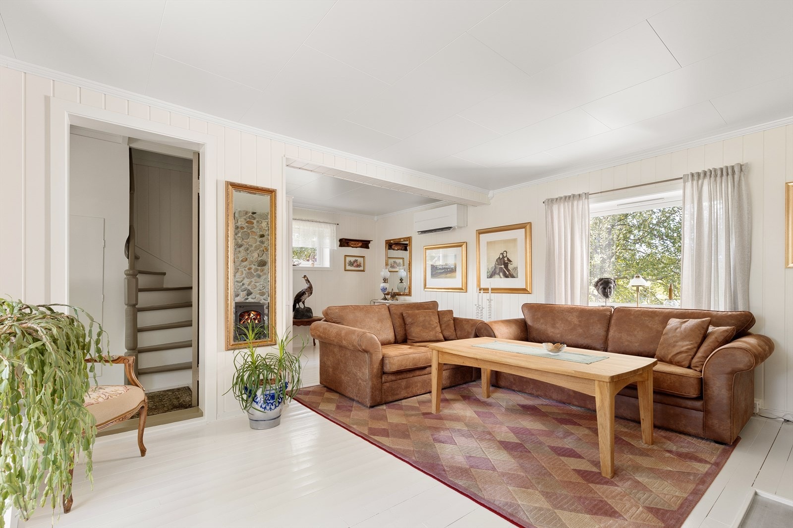 Stuen er av god størrelse og har en sjarmerende atmosfære med malt tregulv og lysmalt veggpanel. Galleribilde