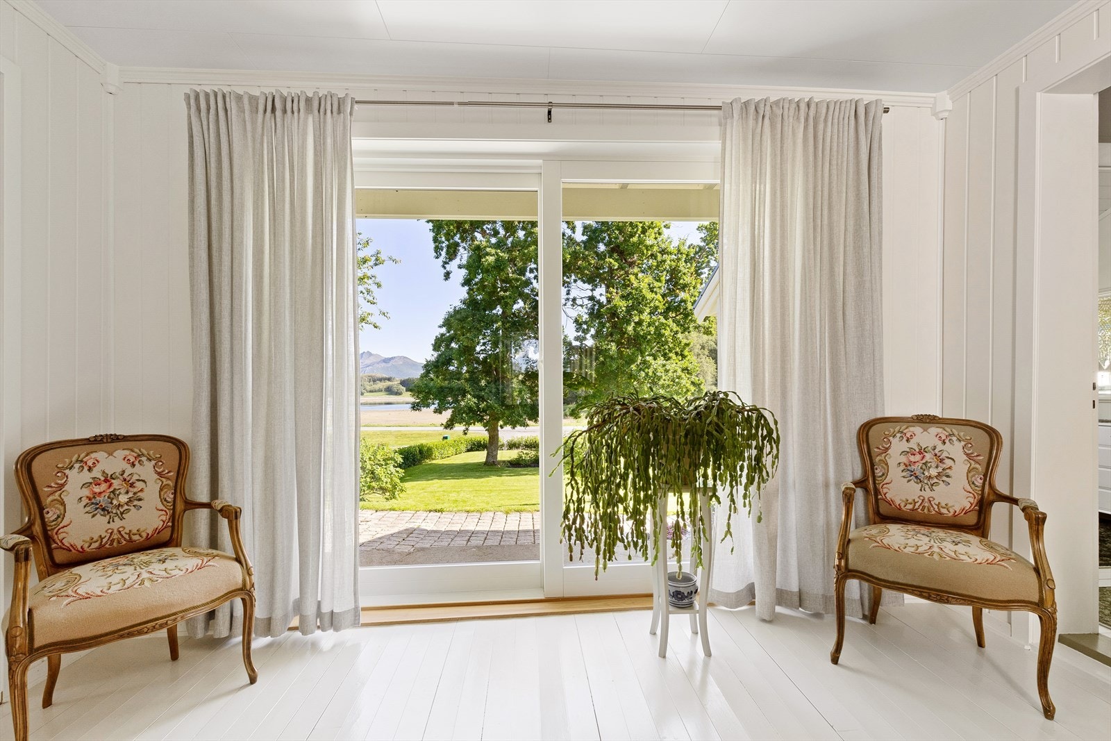 Stor, nyere skyvedør med glassfelt åpner opp til steinlagt areal utenfor stuen. Galleribilde