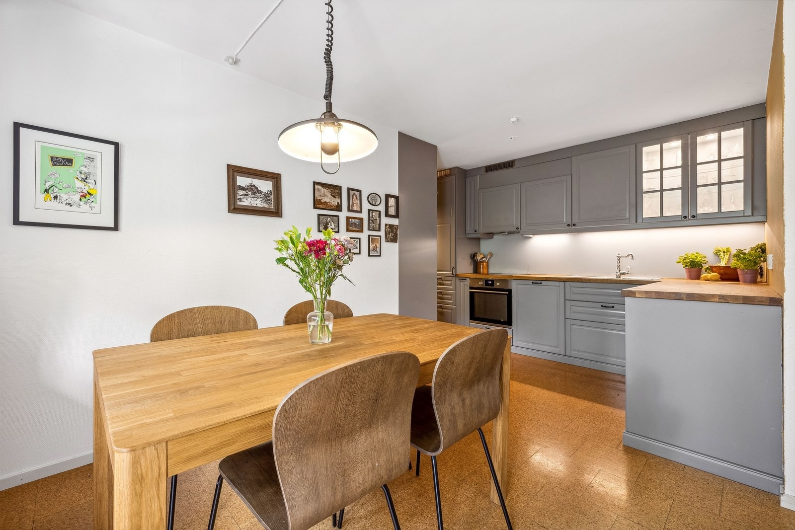 Pent IKEA kjøkkeninnredning fra 2017 med profilerte fabrikklakkerte fronter, heltre benkeplate med nedfelt kum i rustfritt stål, flislignende plater på vegg over benkeplaten, lys montert under overskapene og kjøkkenventilator med kullfilter. Galleribilde