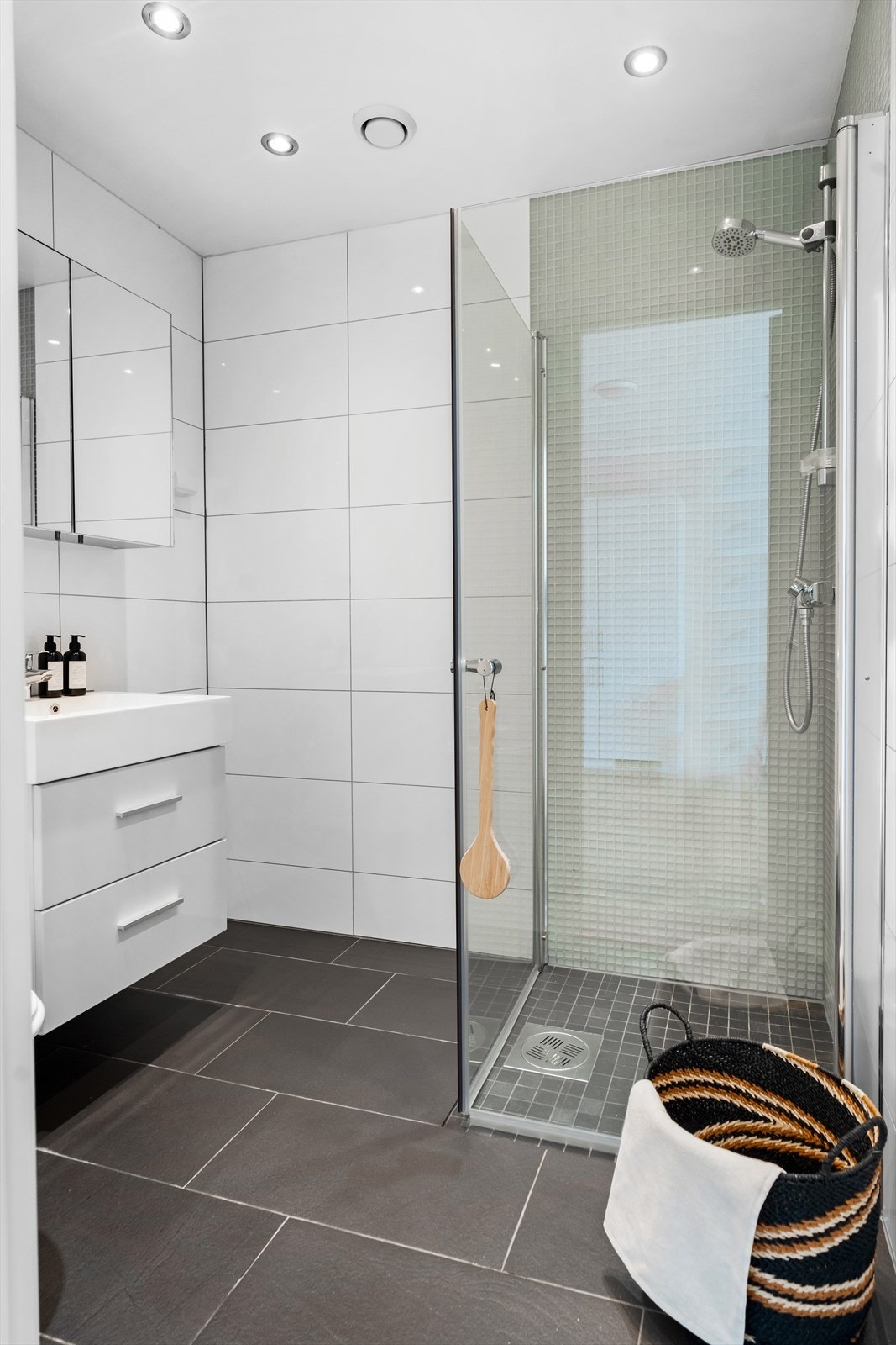 Videre er det satt inn dusj på gulv med dører i herdet glass, veggfestet klosett med innebygget sisterne. Galleribilde