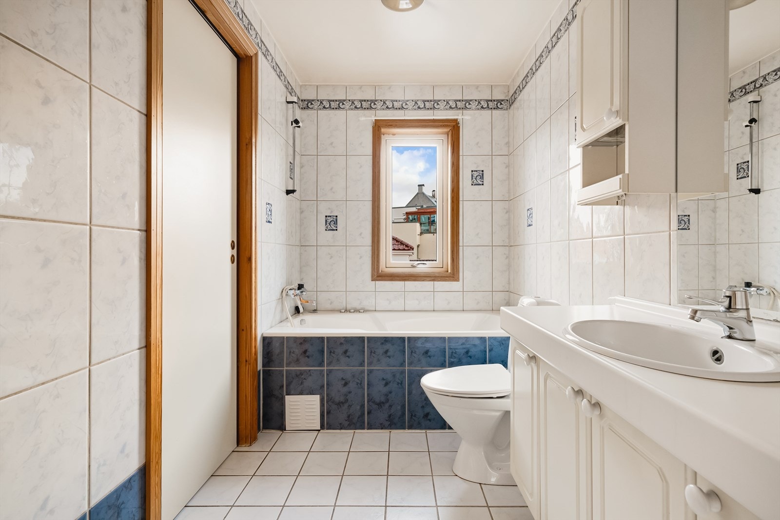 Badet har hvit baderomsinnredning med over- og underskap, servant og klosett, samt innfliset badekar Galleribilde