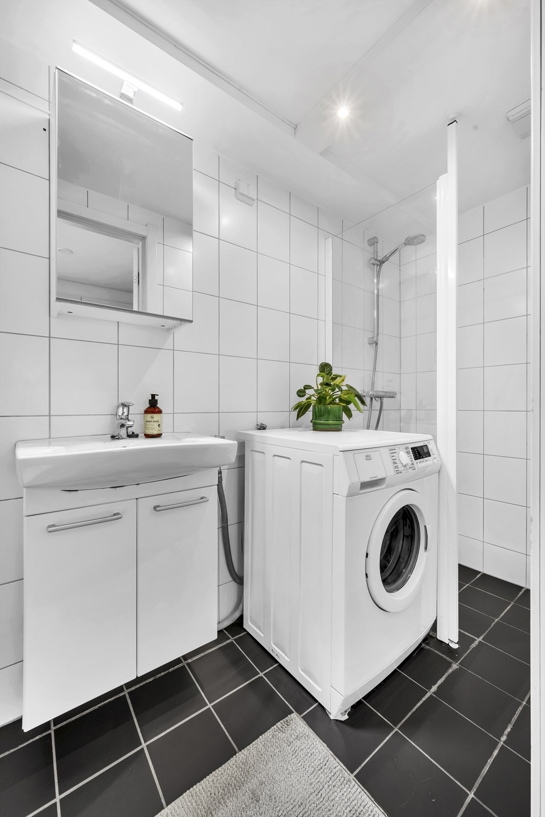 Nøytralt og velfungerende bad fra 2007 med flislagte overflater, gulvvarme og downlights. Det er opplegg for vaskemaskin og mekanisk avtrekk Galleribilde