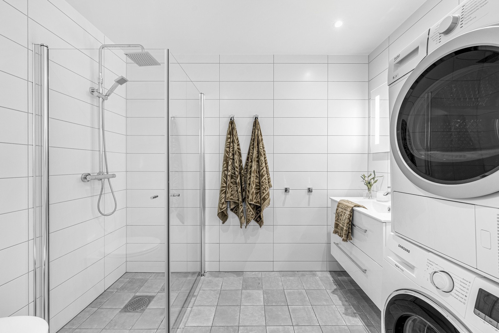 Lyst baderom fra byggeår med fliser på gulv og vegger, samt malt slett himling. Galleribilde