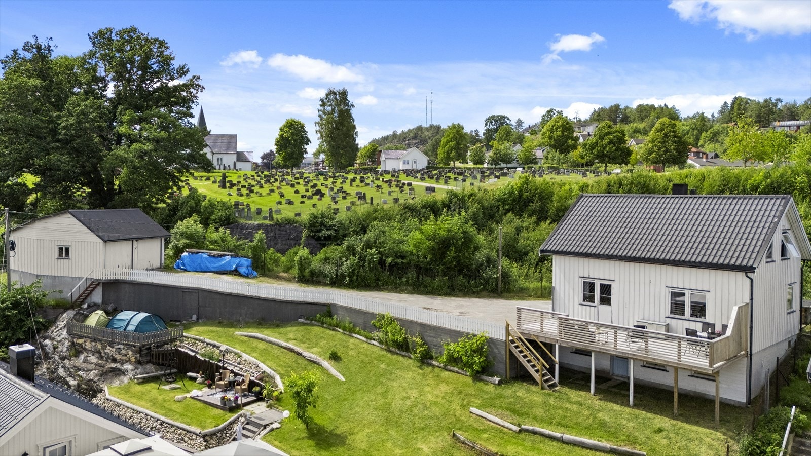 Tomten er helt flat med gruset adkomst og asfaltert gårdsplass. Galleribilde