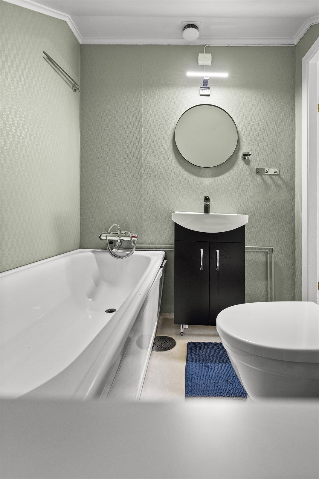 Badet innehar badekar, wc og servant med underskap. Belegg på gulv, og malt tapet på veggene. Galleribilde