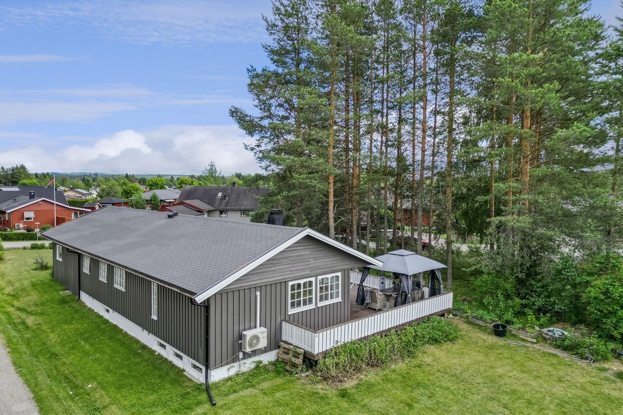 Stor tomt med plen og beplantninger, dels naturtomt med furu mot sør - Asfaltert gårdsplass - Gang-/sykkelsti langs tomtegrense i nord Galleribilde