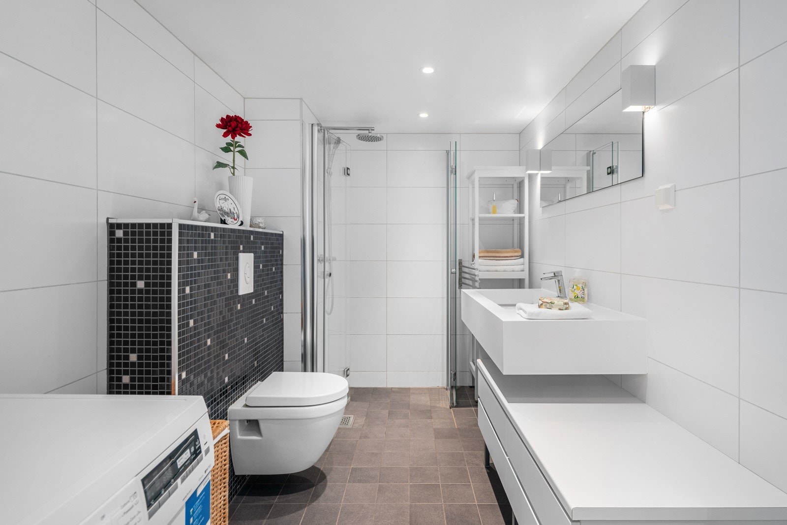 Leilighetens bad fremstår som moderne med nye veggfliser fra 2018, og fliser på gulv med gulvvarme. Galleribilde