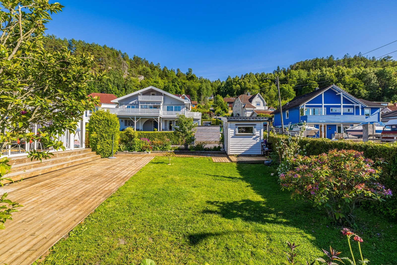 Tomten er tilnærmet flat, og omkranser flere av husets sider. Galleribilde